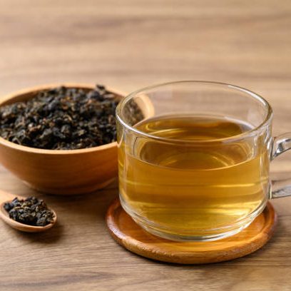 Oolong tea in cup glass with dried Oolong tea leaves on wooden background, Healthy drink